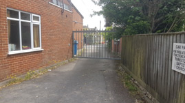 image shows the side entrance to the carpark to the right of the church hall off Loch Road. The gate is closed